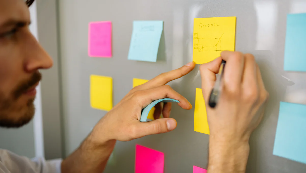 homem organizando post-its na parede, ilustrando TDAH e organização de rotina